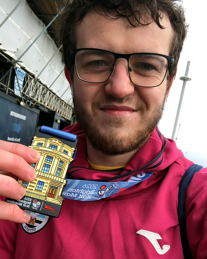 William holding up his 2026 Brighton Half Marathon finisher's medal