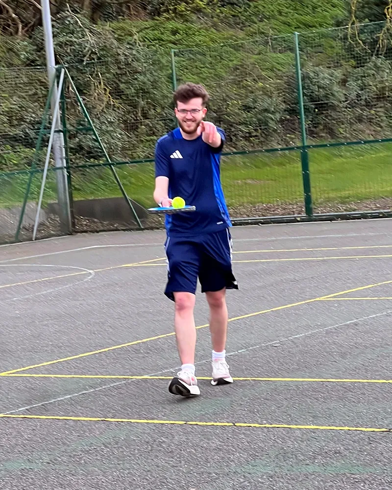 William playing tennis on an outdoor court